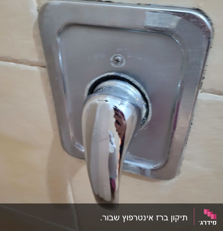 ידית ברז מתכתית על קיר אריחים